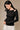 Black fitted long sleeve top with gold hardware shoulder cutout