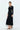 Side view of women's black long sleeve stretch knit midi dress