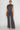 Front view of charcoal gray ruched wide leg pants set featuring an asymmetrical draped top and full-length flowing pants