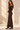 Side view of chocolate brown ribbed knit maxi dress showing fitted silhouette and crossed off shoulder neckline