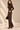 Side view of chocolate brown knit barrel leg pants showing relaxed silhouette, seam details and wide leg