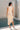 Back view of sleeveless cream sweater knit dress with asymmetrical fringe detail