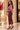 Side view of eggplant purple knit maxi skirt showing fitted silhouette, side slit and gold button waistband