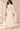 Back view of ivory faux leather midi skirt with fitted waistband and long pleated chiffon hem