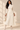 Front view of ivory faux leather midi skirt with asymmetrical overlay and flowing pleated chiffon hem