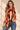 Orange abstract foil print lightweight scarf with brown and cream wave pattern styled around a woman's neck