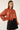 Angled front view of rust pearl embellished chiffon blouse showing the neck tie bow, textured fabric and voluminous sleeves