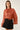 Front view of rust pearl embellished tie neck chiffon blouse with shimmering fabric, tonal pearls and balloon sleeves