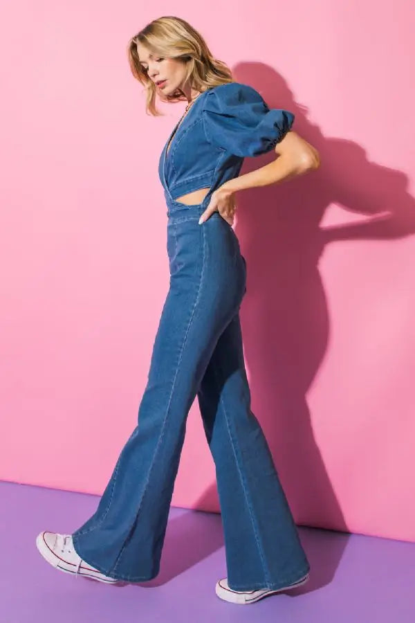 Weezie D Cut Out Stretch Flare Denim Jumpsuit in indigo blue features a criss cross v-neckline with front & side cut outs. Exaggerated elastic puff short sleeves. Clean hidden back zipper. Cotton, polyester, spandex blend offers great stretch. Wear to brunch parties & special occasion events any season. 