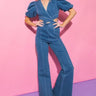 Weezie D Cut Out Stretch Flare Denim Jumpsuit in indigo blue features a criss cross v-neckline with front & side cut outs. Exaggerated elastic puff short sleeves. Clean hidden back zipper. Cotton, polyester, spandex blend offers great stretch. Wear to brunch parties & special occasion events any season. 